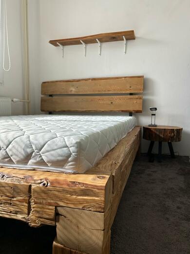 postel z ručně tesaných trámů